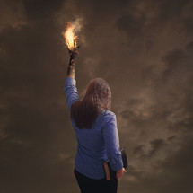 Woman holding a bible with a flame of fire coming from her extended hand.