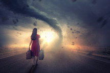 Woman walks towards a tornado and bright sunset