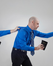 man with a Bible being held back 