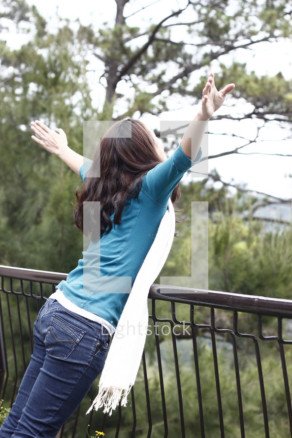 woman pretending to fly leaning over a railing 