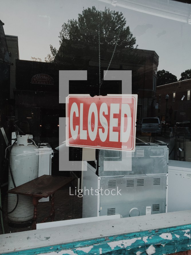 closed sign hanging in a shop window 