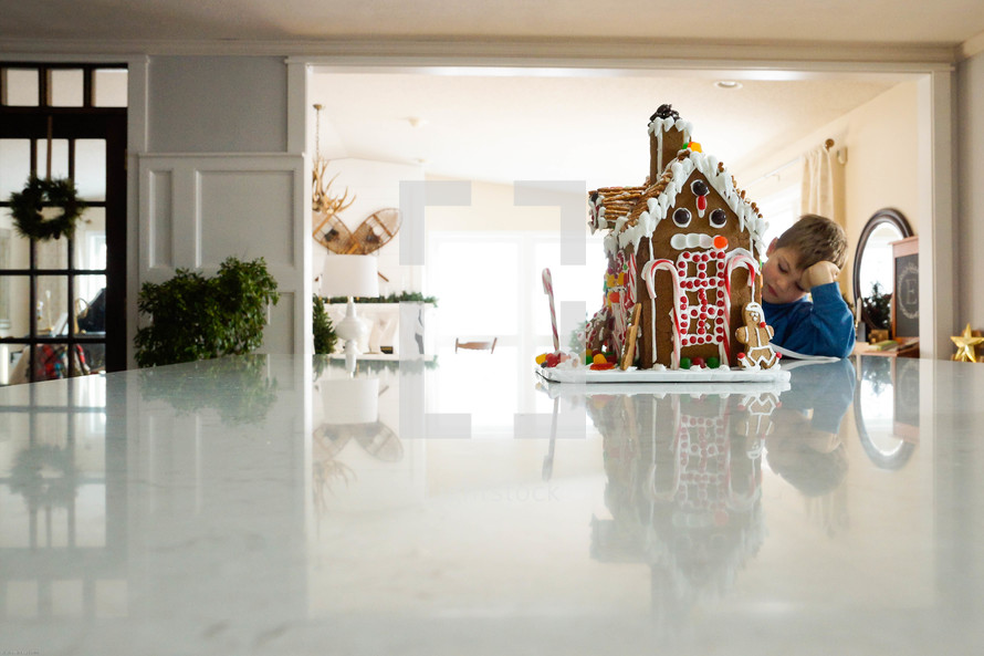 boy and gingerbread house on a kitchen counter 