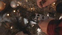 Man hanging the word Hope on a Christmas tree