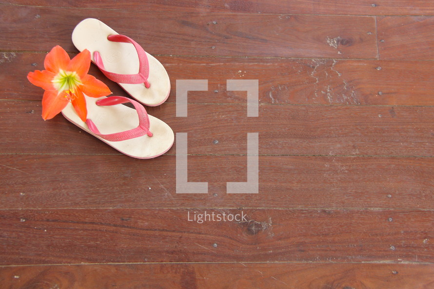 Child's flip flops on wooden floor with tropical flower orphan orphanage mission 
