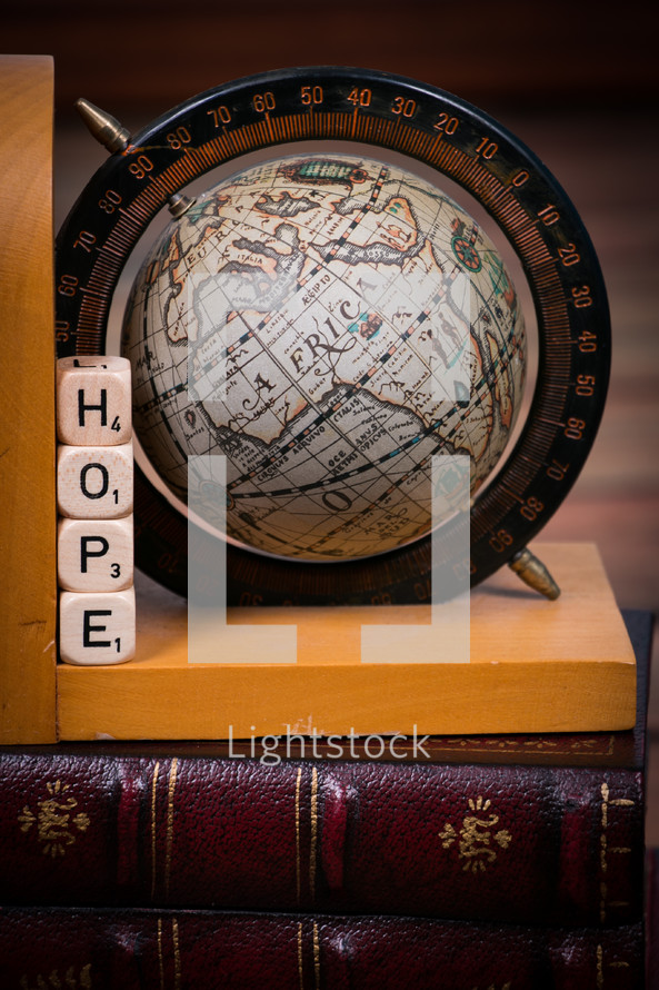 A globe bookend and dice spelling "hope" on a leather Bible.