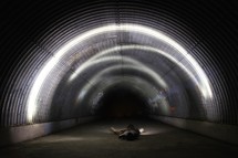a man lying on the ground in a dark tunnel 