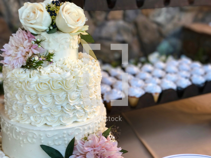 a wedding cake and cupcakes on a table 
