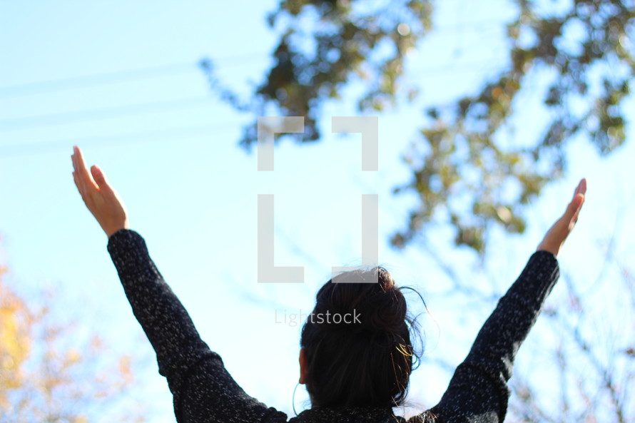 a woman with raised hands outdoors 