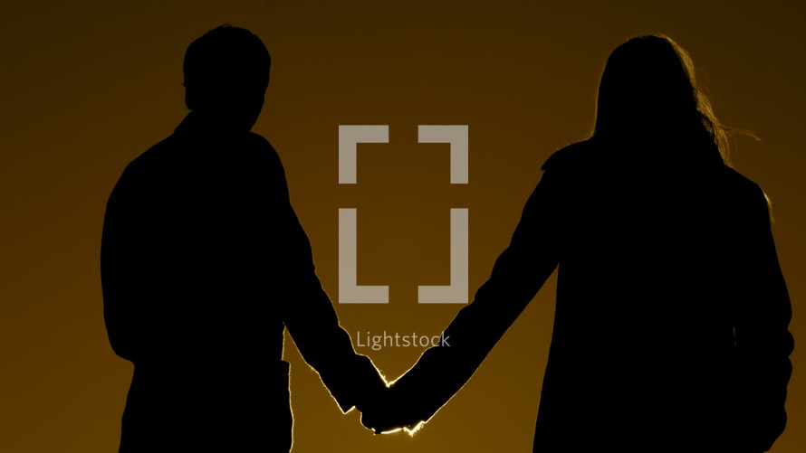 Silhouette of couple holding hands in the moonlight.