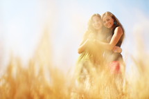 friends hugging in a field of golden wheat 