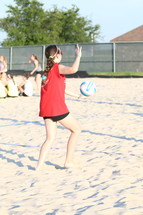 a teen girl playing volleyball in the sand 