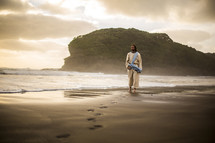 Jesus walking on a shore leaving footprints in the sand 