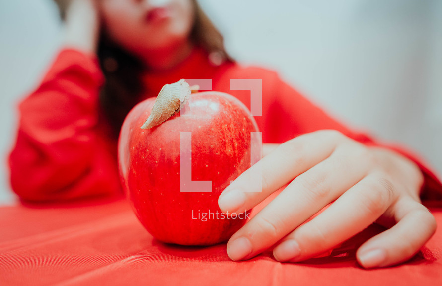 a woman holding a red apple 