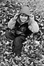 boy child playing in a leaf pile