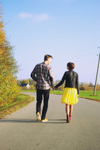 a couple walking holding hands down a rural street 