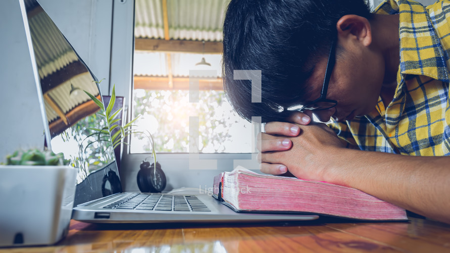Young male praying with computer laptop, Online church in home, Home church during quarantine coronavirus Covid-19, Religion concept.