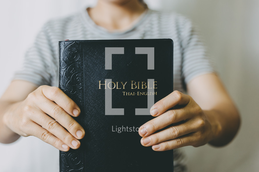 person holding out a Holy Bible 