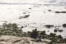 Couple sitting on rocks on the beach.