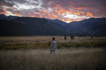 a man standing in a field at sunset 