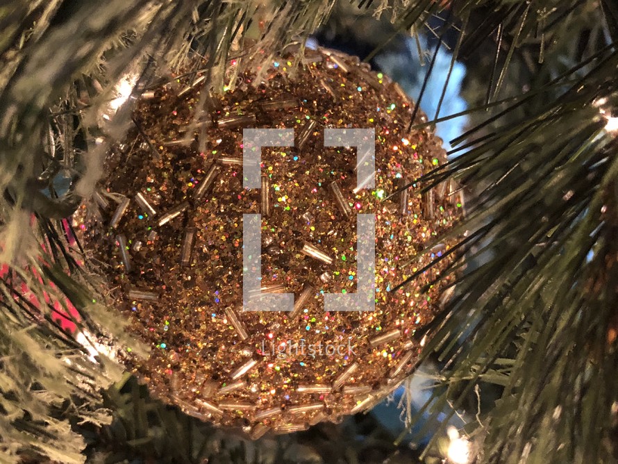 sparkly gold ball ornament on a Christmas tree, close up