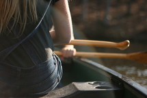 woman sitting on a boat holding paddles 