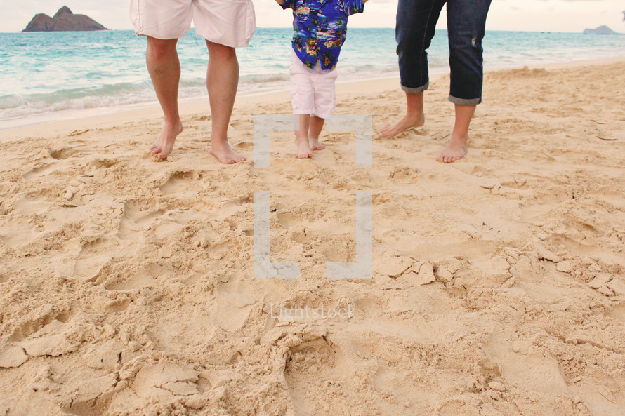 Father, mother and young son walking on the beach.