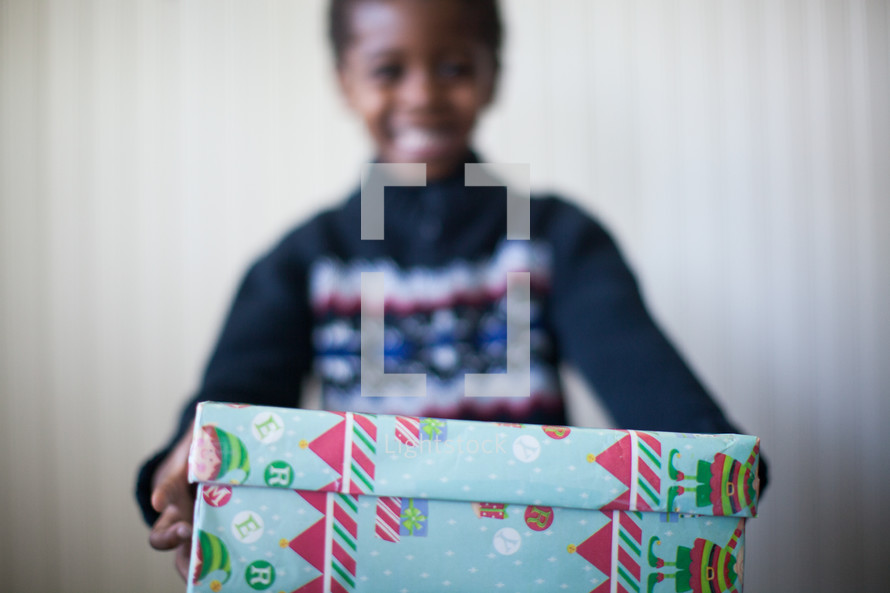 boy child holding a wrapped Christmas gift 