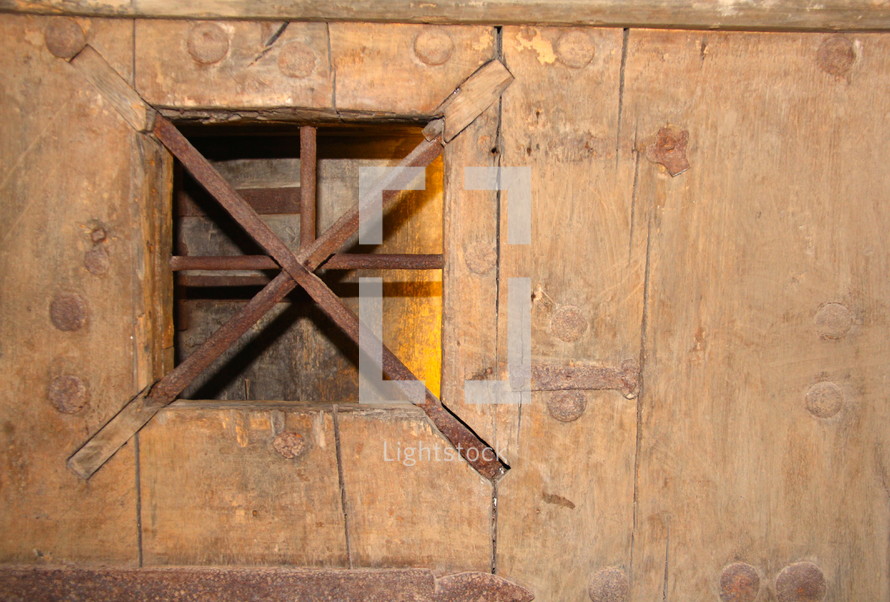 barred window on a wood door 