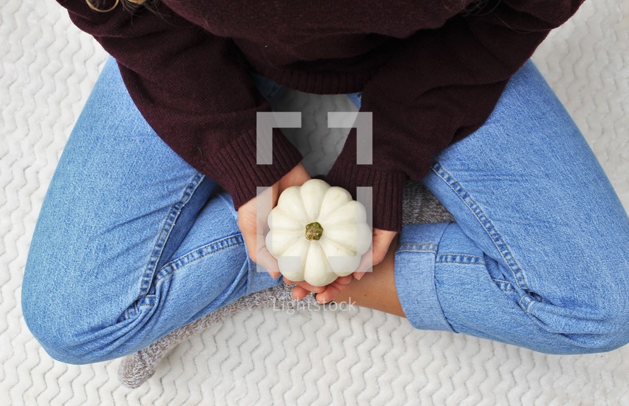 a woman holding a white pumpkin 