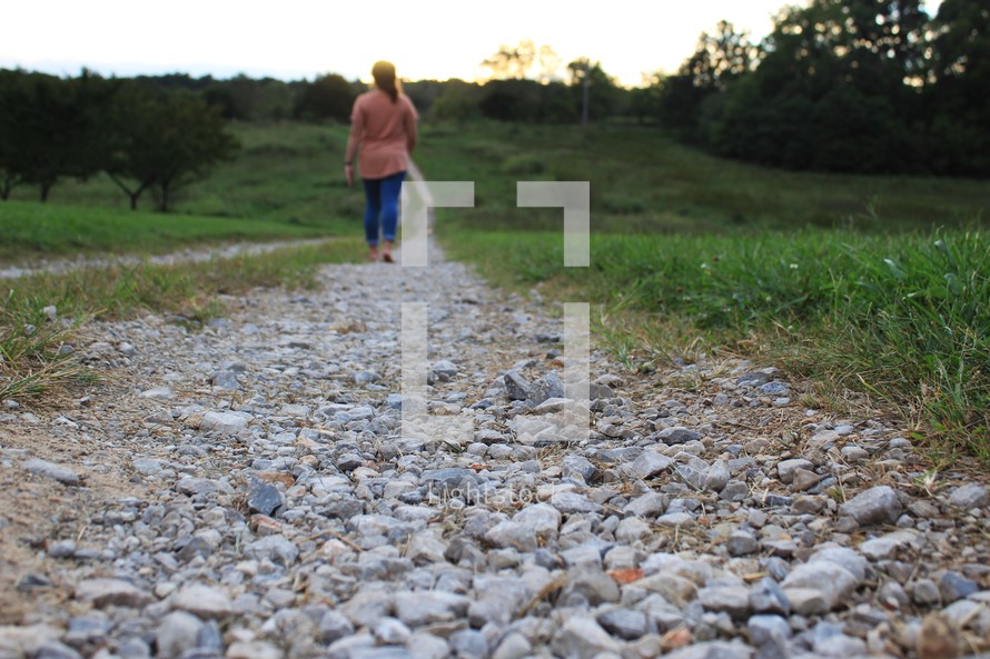 woman walking down a gravel road 