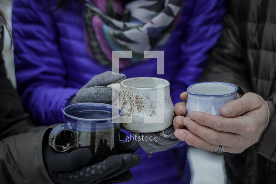 people standing outdoors in winter holding mugs 