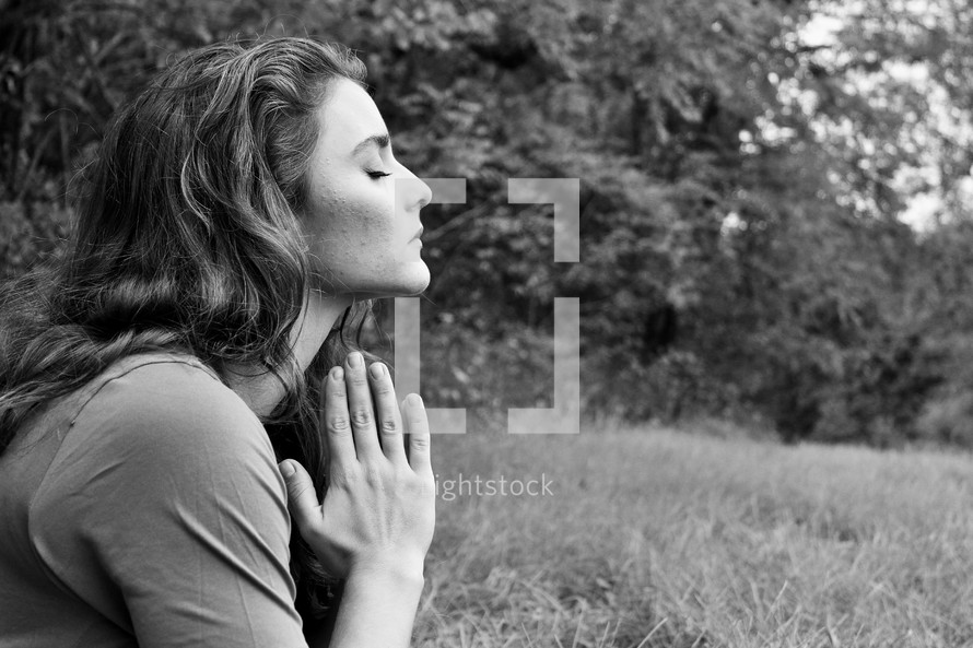 a woman praying outdoors