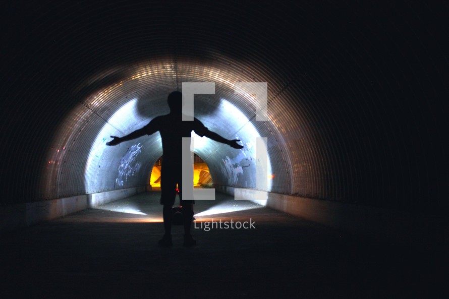 silhouette of a man standing in a dark tunnel 
