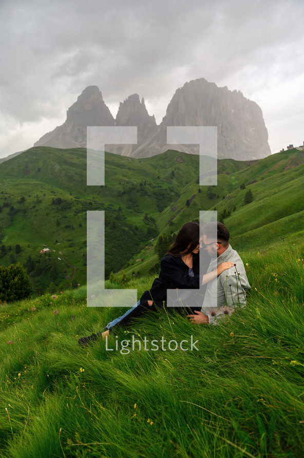 a couple snuggling on a mountainside 