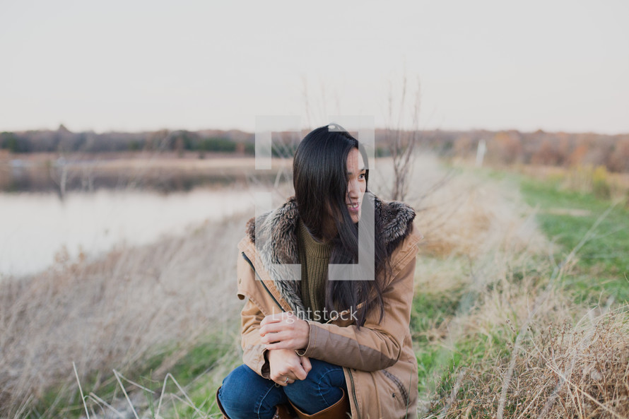 young woman by a lake shore in fall 