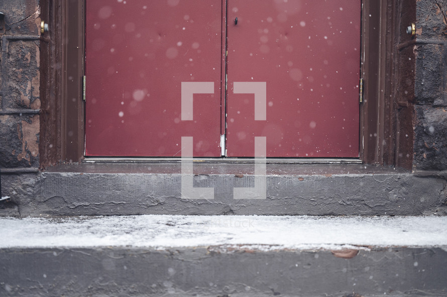 snow in front of red church doors 