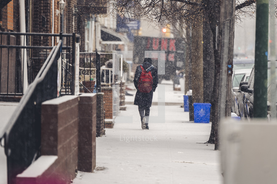a person walking on a sidewalk in snow 