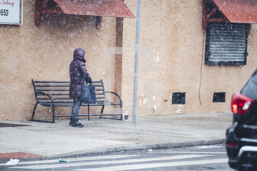 person waiting on a city sidewalk in winter 