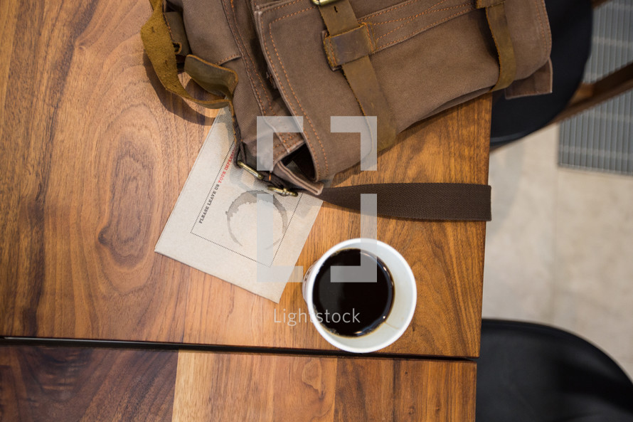 coffee cup and backpack on a wood table 
