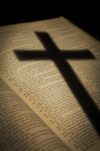 shadow of a cross on the pages of a Bible opened to the passion account