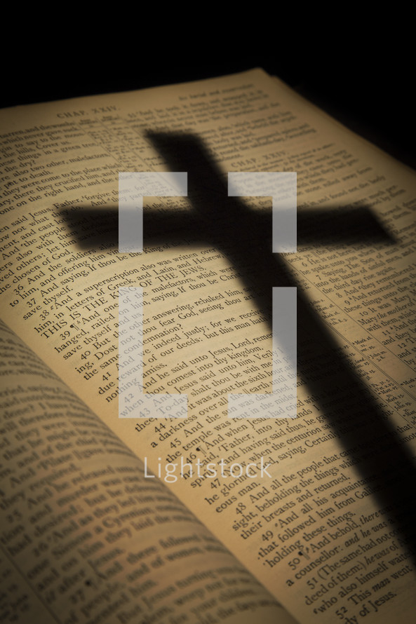 shadow of a cross on the pages of a Bible opened to the passion account