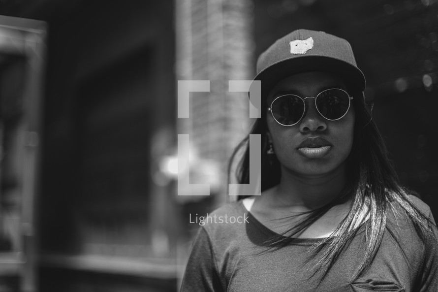 face of an African American woman in a ball cap and sunglasses 