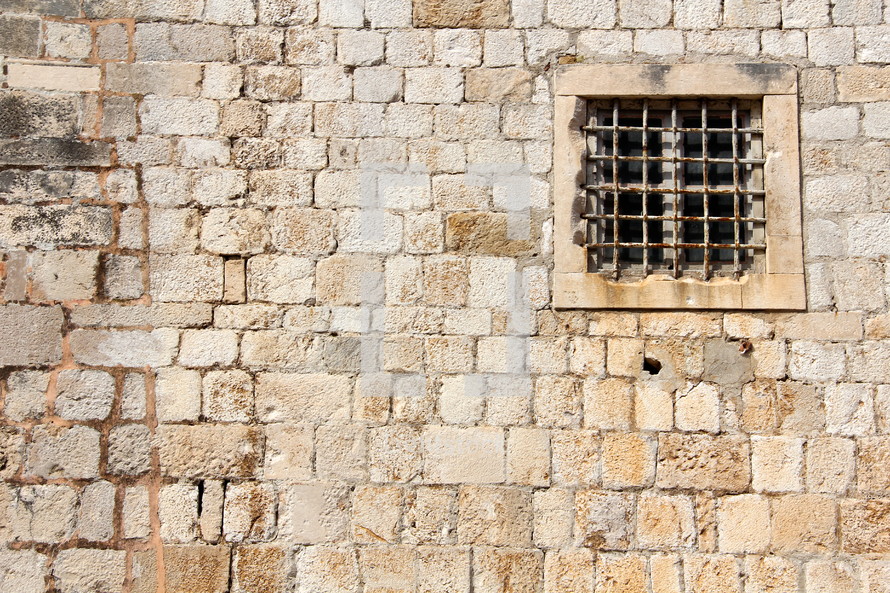 Barred window in ancient stone wall