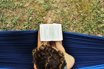 a woman reading a Bible on a hammock 