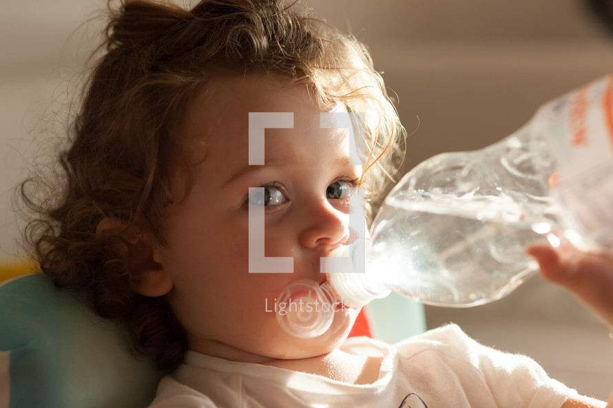 toddler girl drinking from a water bottle 