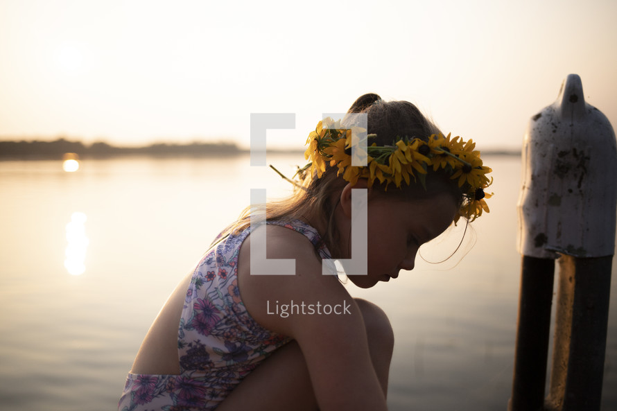 a girl with flowers in her hair with a lake in the background 
