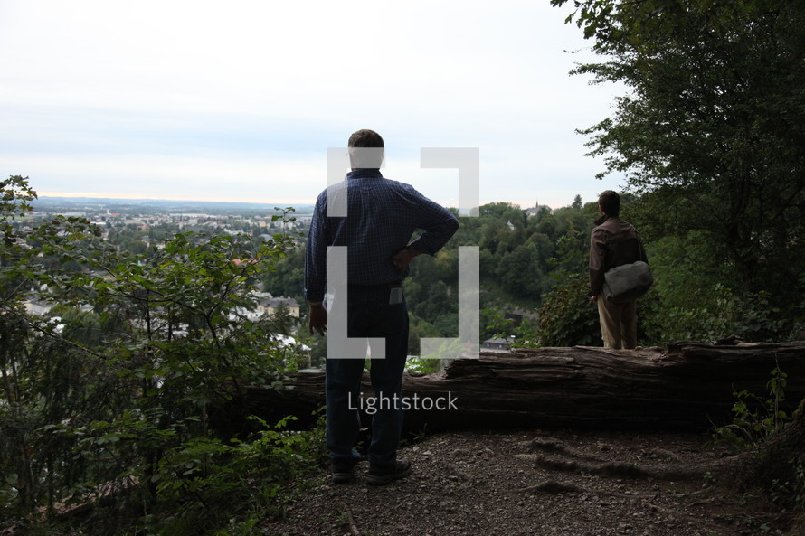 men standing on a mountain top looking out 