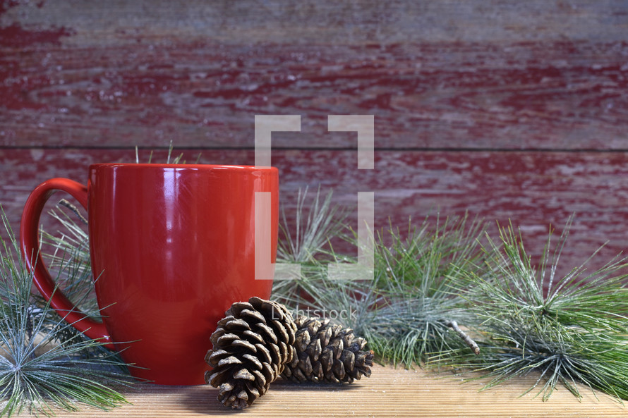red mug, pine cones, and Christmas greenery 