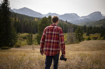 a man in a field holding a camera 