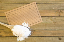 Recipe card and wooden spoon with flour 